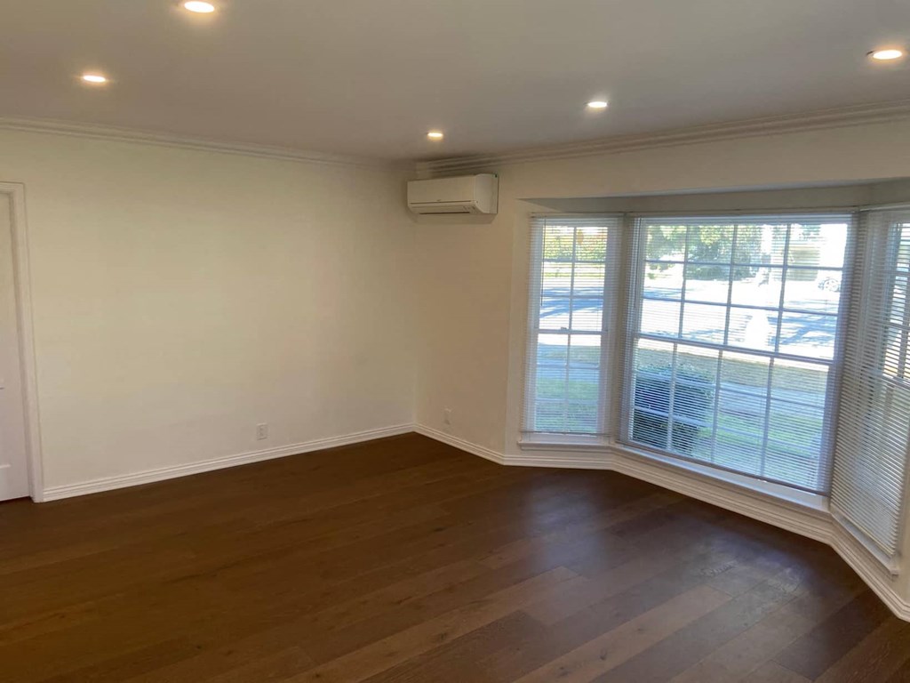 an empty living room with wood floors and a window
