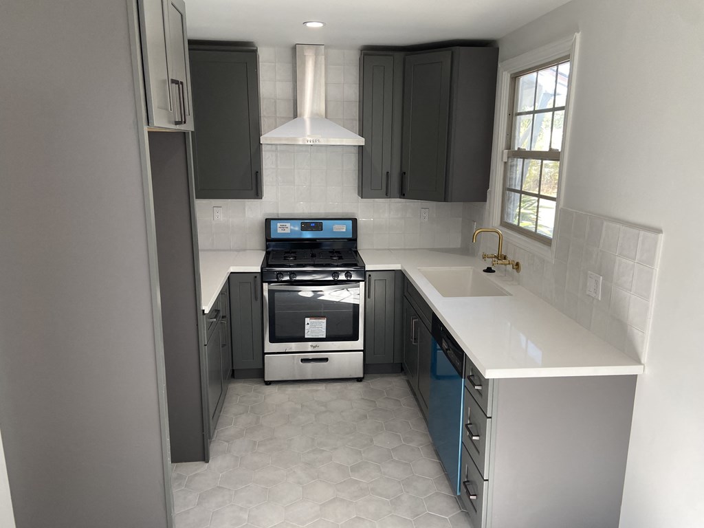 an empty kitchen with black cabinets and a white counter top