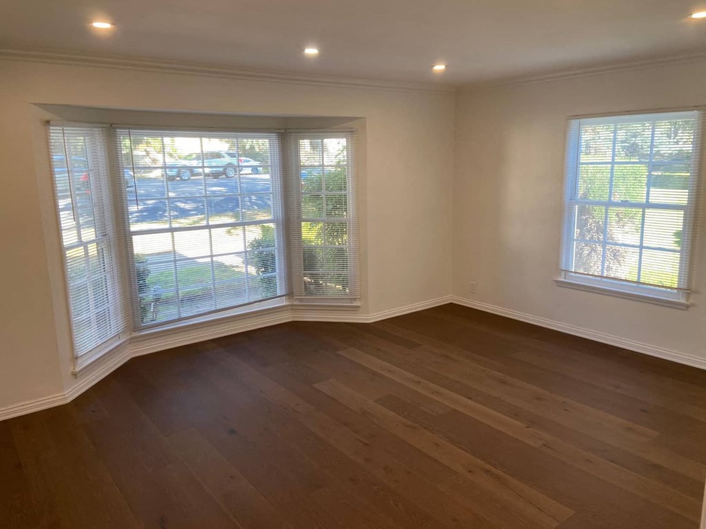 an empty living room with three windows and wood floors