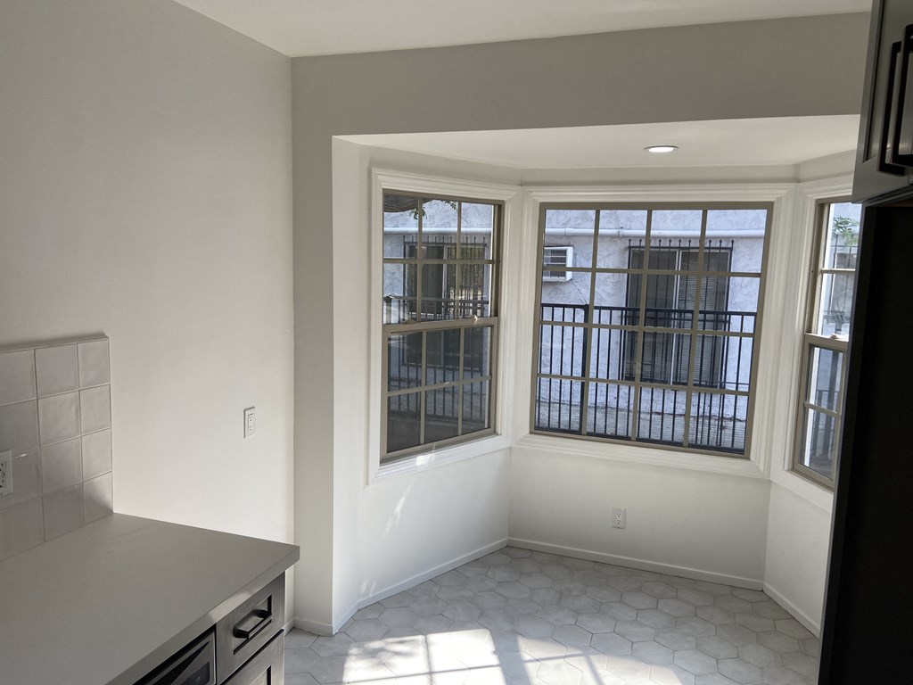 an empty living room with a window and a kitchen