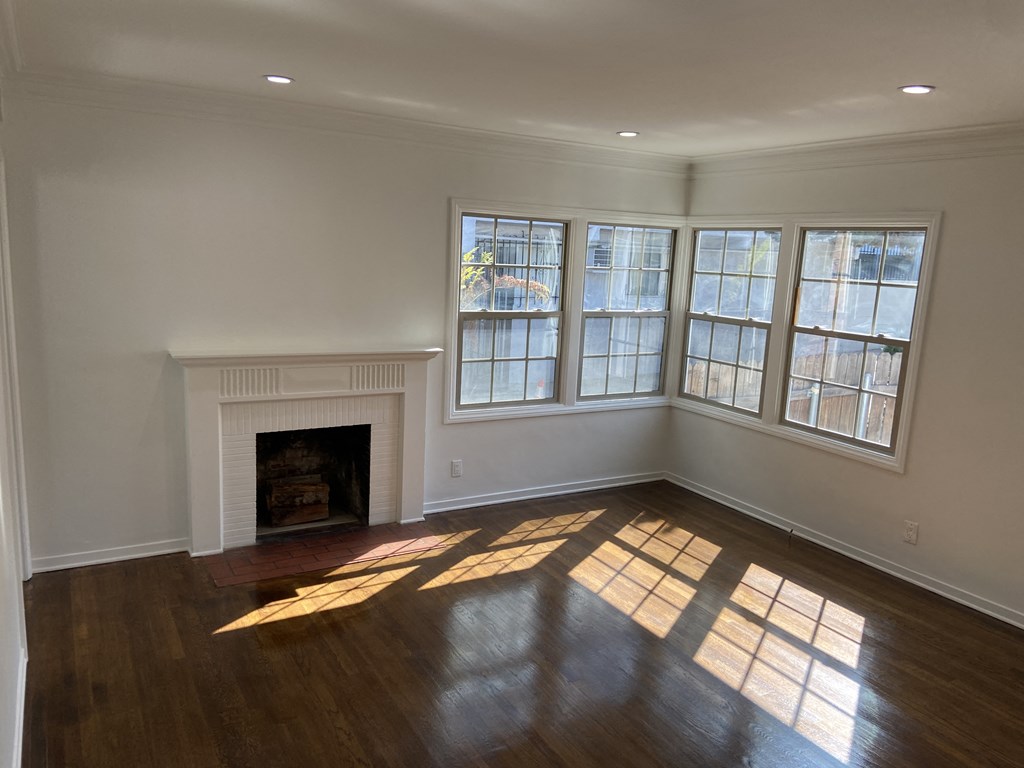 an empty living room with windows and a fireplace