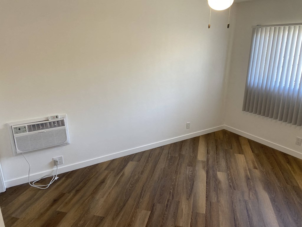 a living room with wood flooring and an air conditioner on the wall