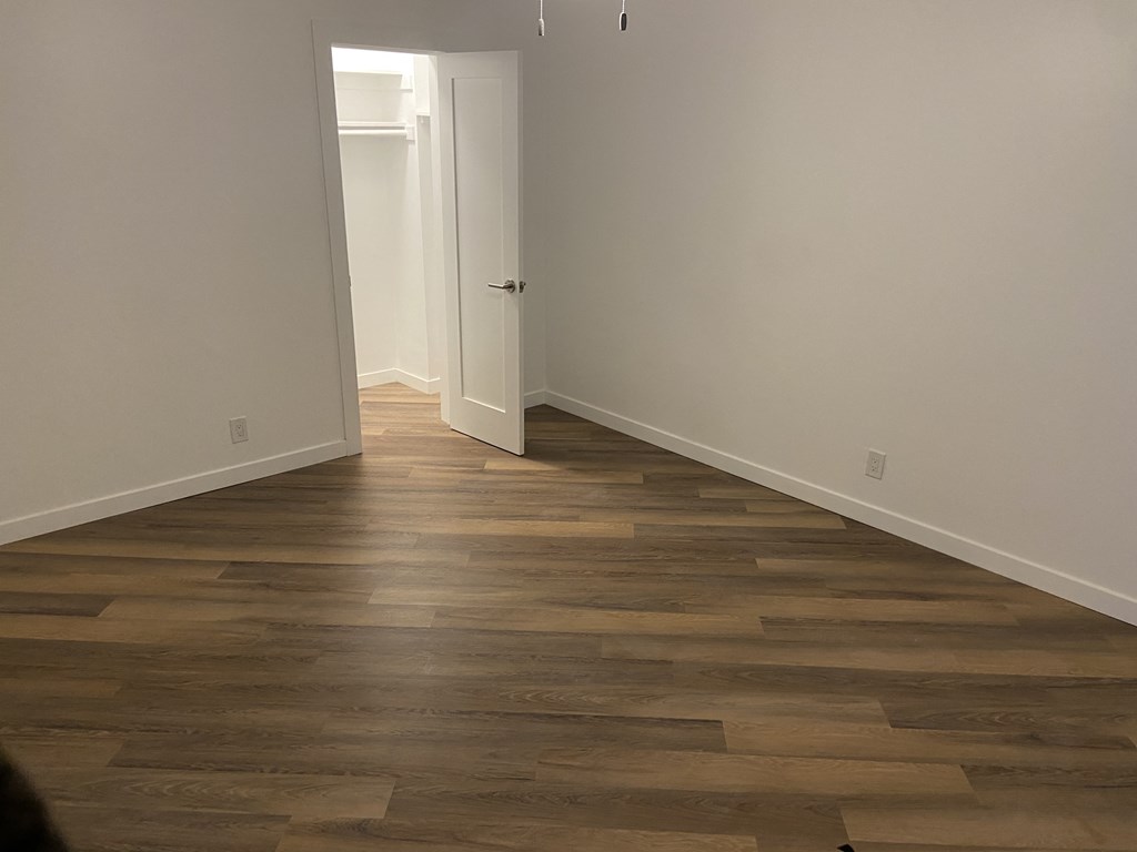 a room with wooden floors and white walls and a door