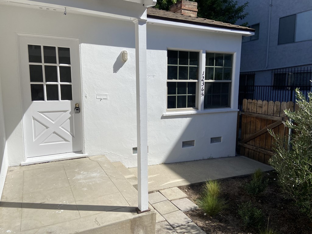 a small white house with a white door and a driveway