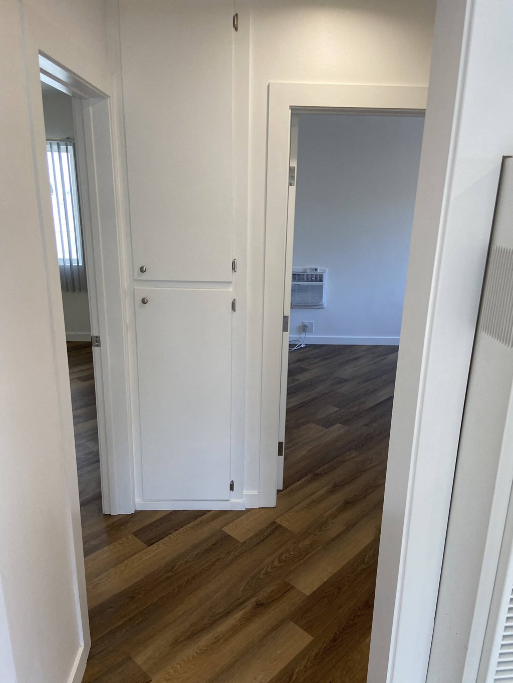 a bedroom with a closet and a hallway with wood flooring