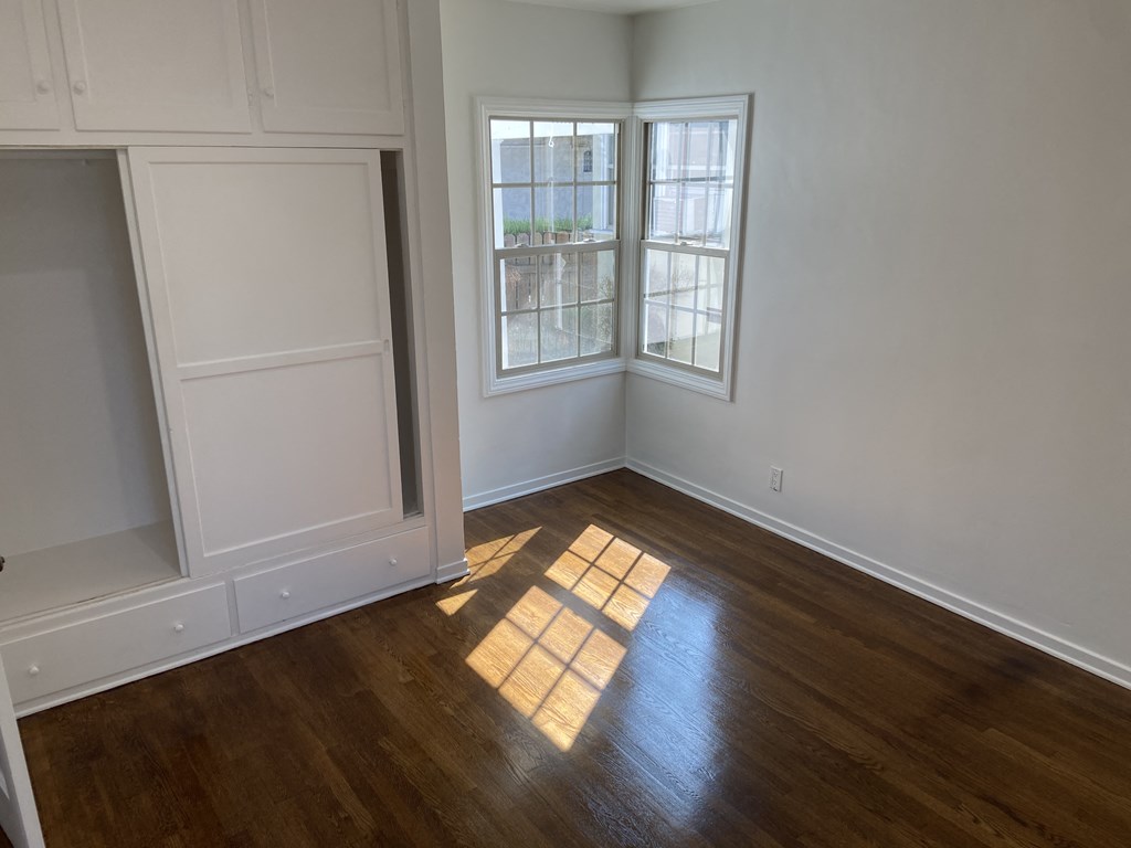 an empty living room with wooden floors and a window