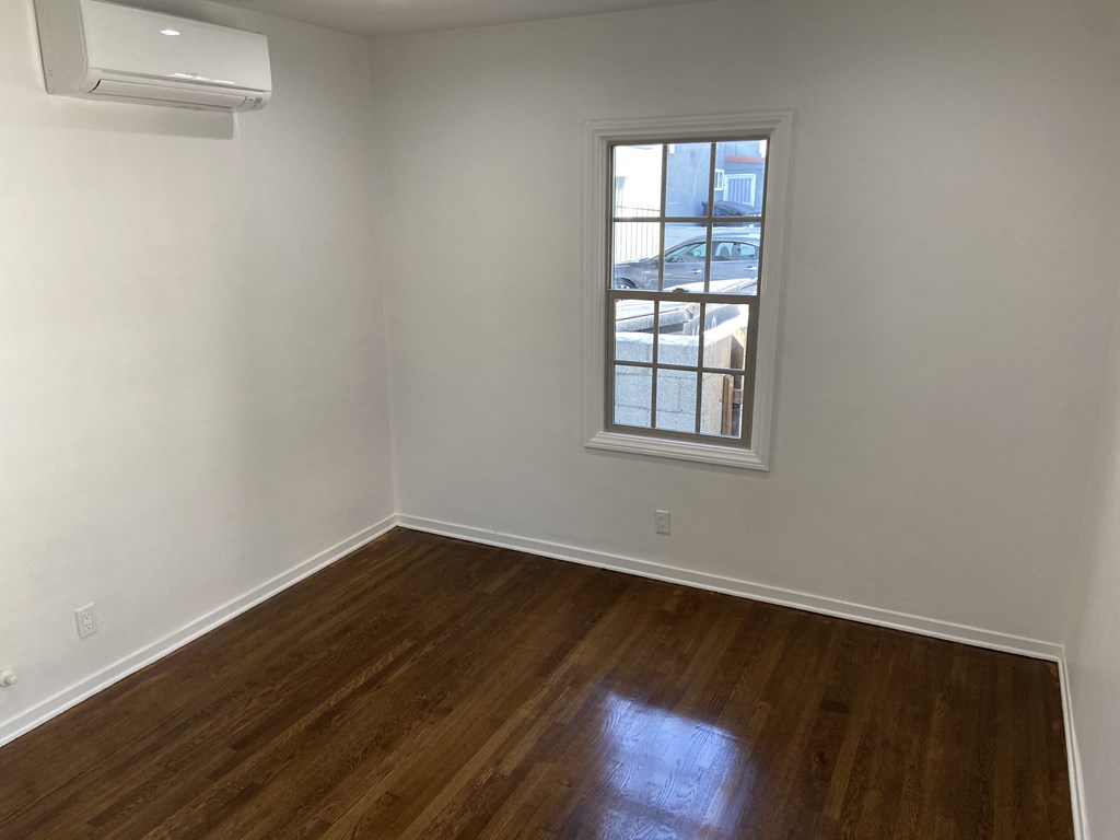 an empty room with wooden floors and a window