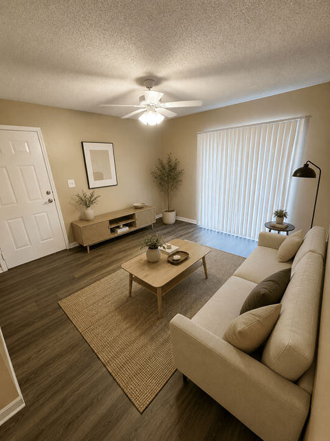 A living room with a couch, coffee table, and a ceiling fan.