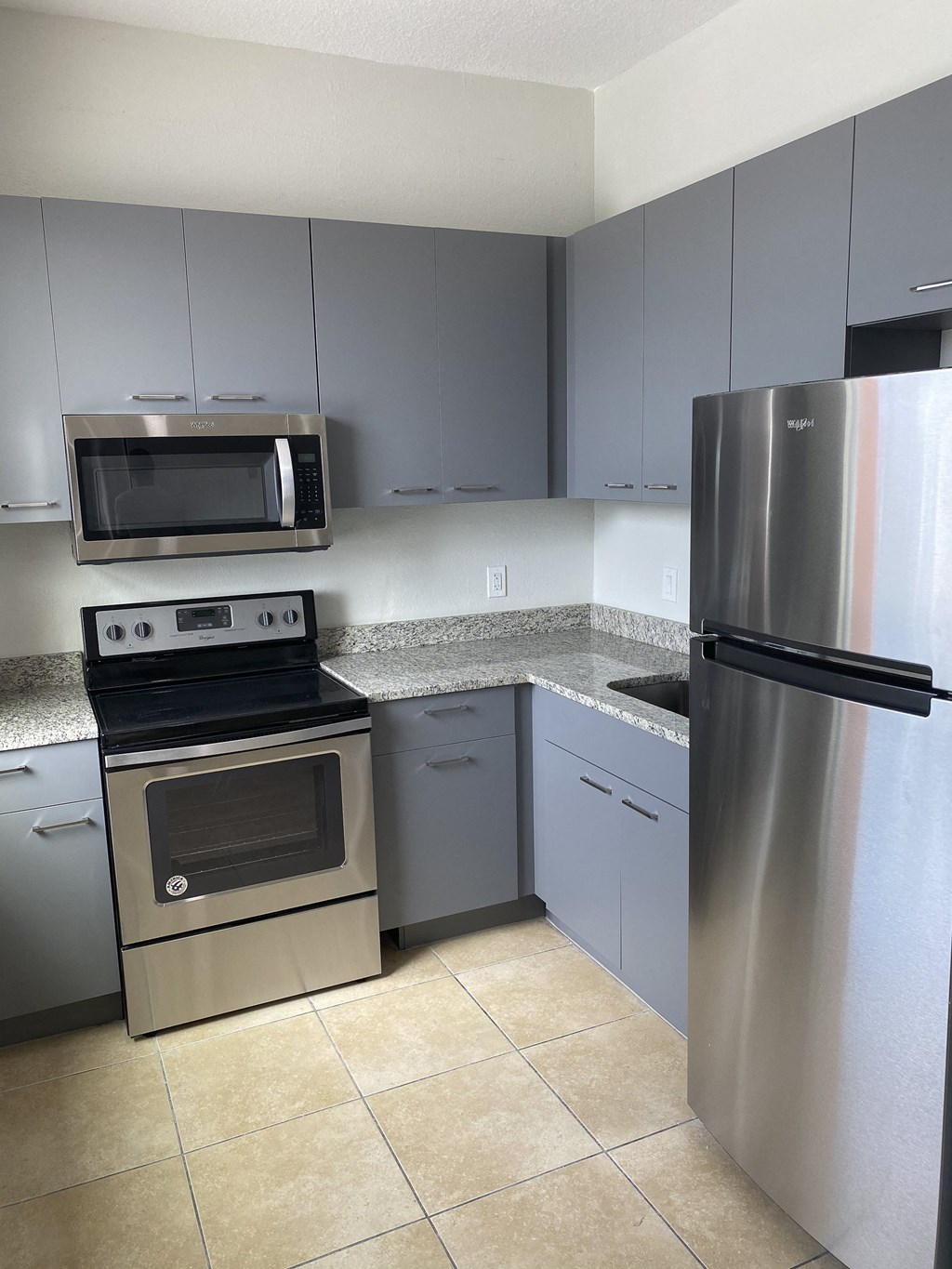 a kitchen with gray cabinets and stainless steel appliances at Colonial Drive Apartments, Orlando, FL