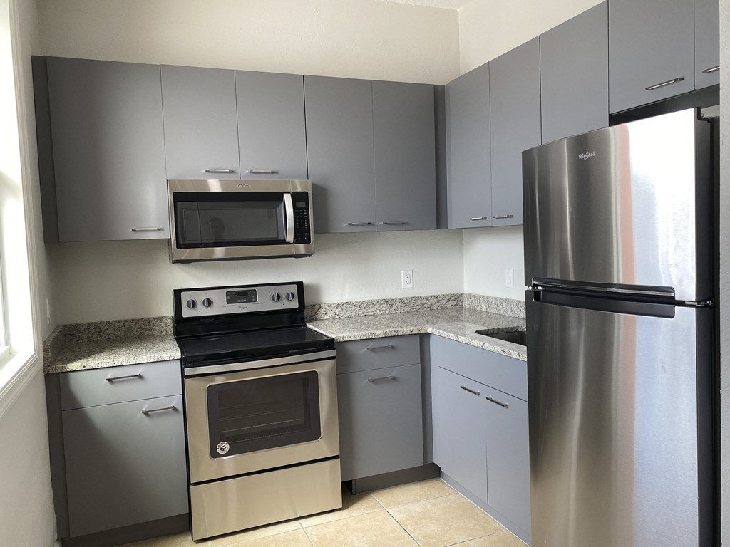a kitchen with gray cabinets and stainless steel appliances at Colonial Drive Apartments, Florida