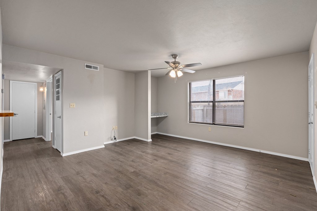 an empty living room with a ceiling fan and a window