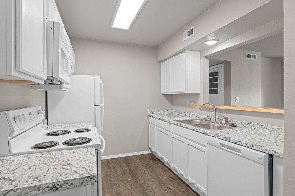 an empty kitchen with white appliances and granite counter tops