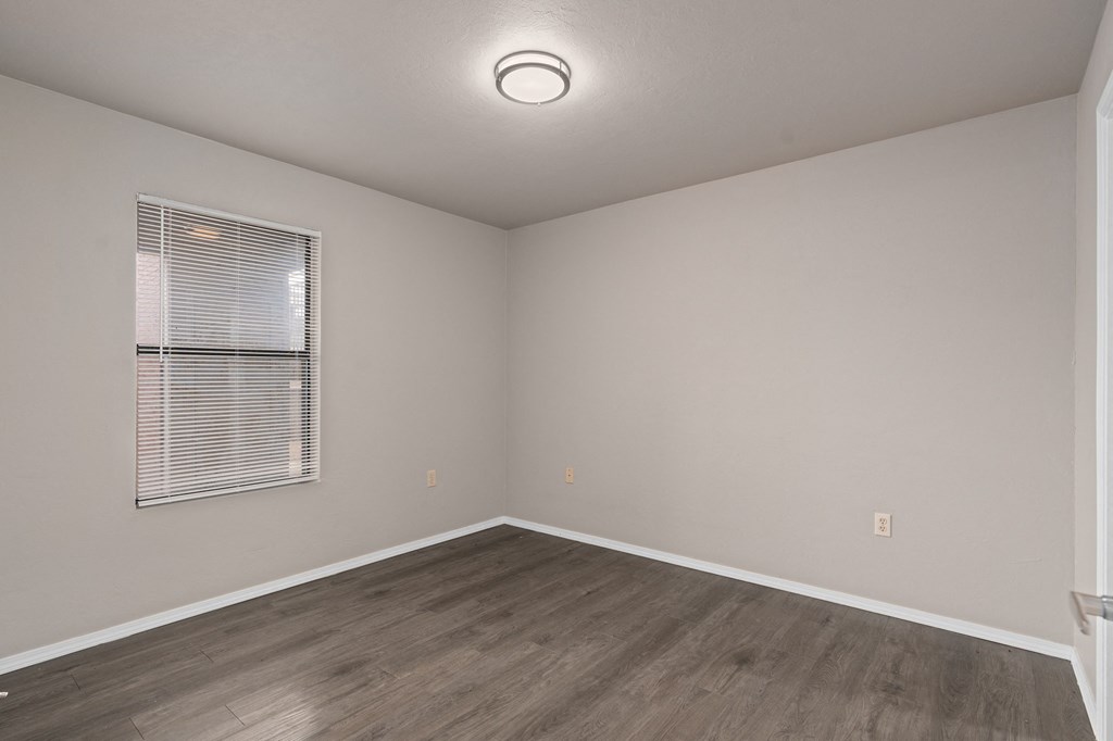 an empty room with wood floors and a window