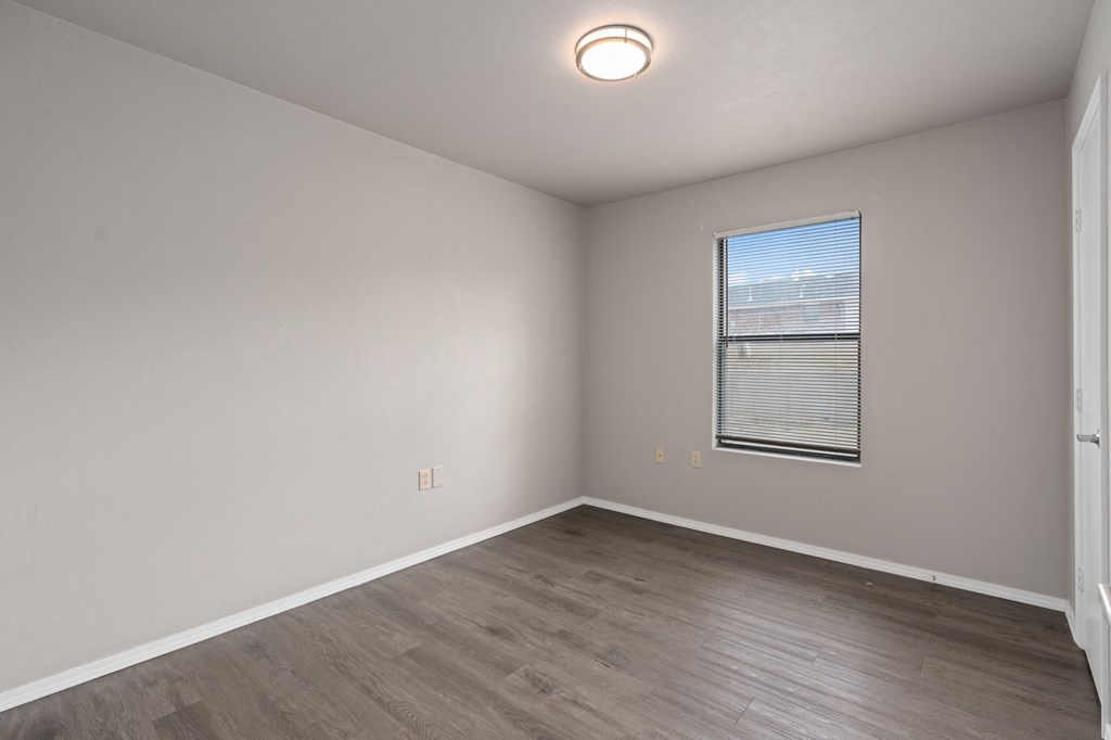 an empty living room with wood floors and a window