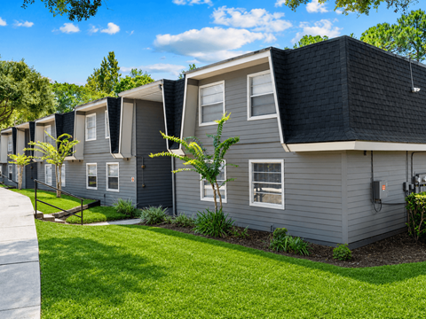 A row of houses with grey siding and black roofs.