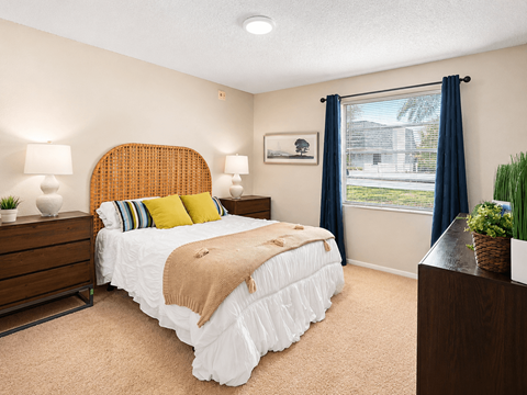 A bedroom with a bed, nightstand, and window.