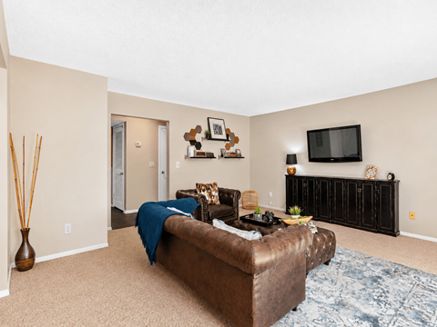 A living room with a brown couch and a flat screen TV mounted on the wall.