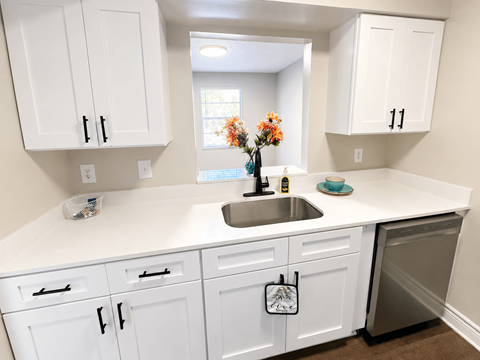 A kitchen with white cabinets and a sink.