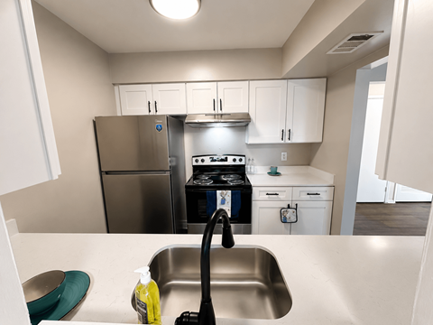 A kitchen with a stove, sink, and cabinets.