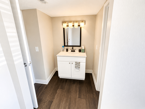 A white bathroom vanity with a mirror and lights above it.