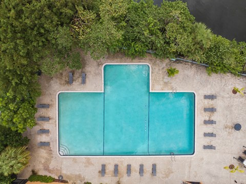 an overhead view of an infinity pool with trees and a blue water
