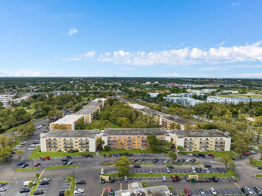an aerial view of an apartment complex with a parking lot and trees