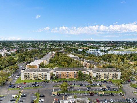 an aerial view of an apartment complex with a parking lot and trees at Cypress Grove, Lauderhill, FL