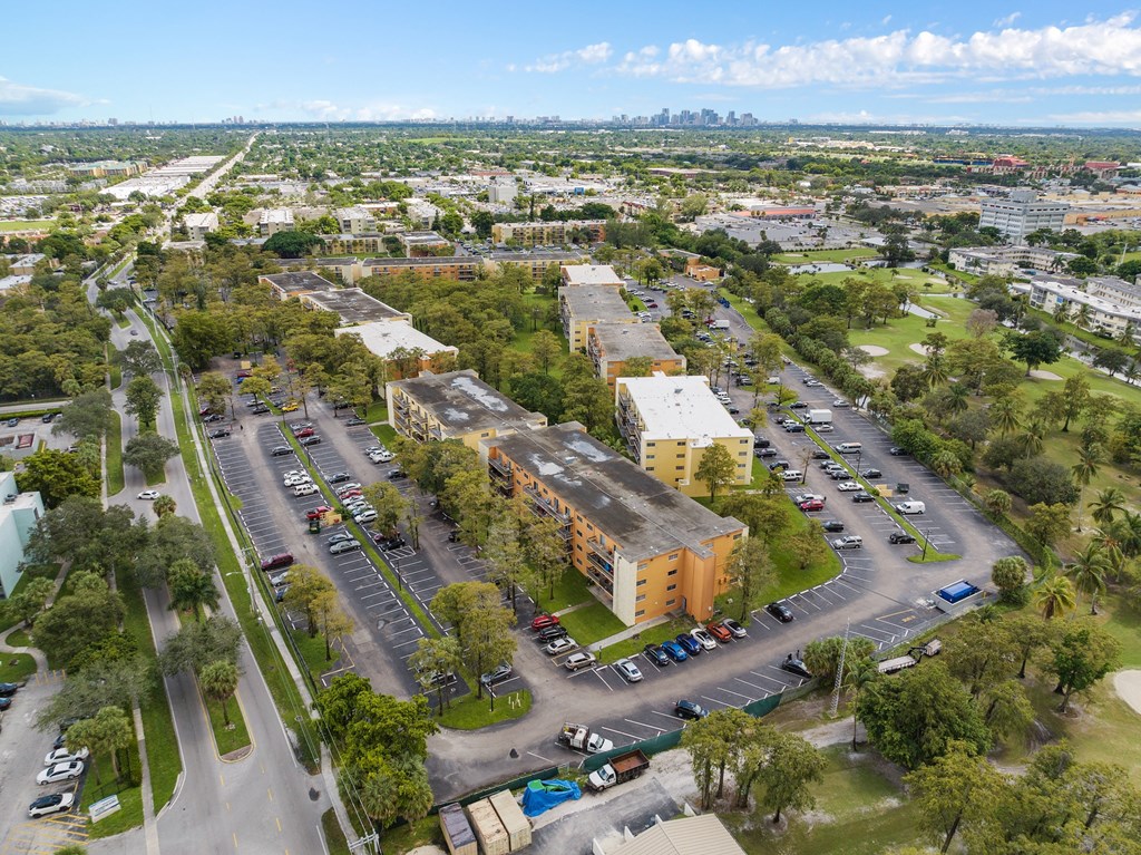 an aerial view of an empty parking lot with buildings and trees