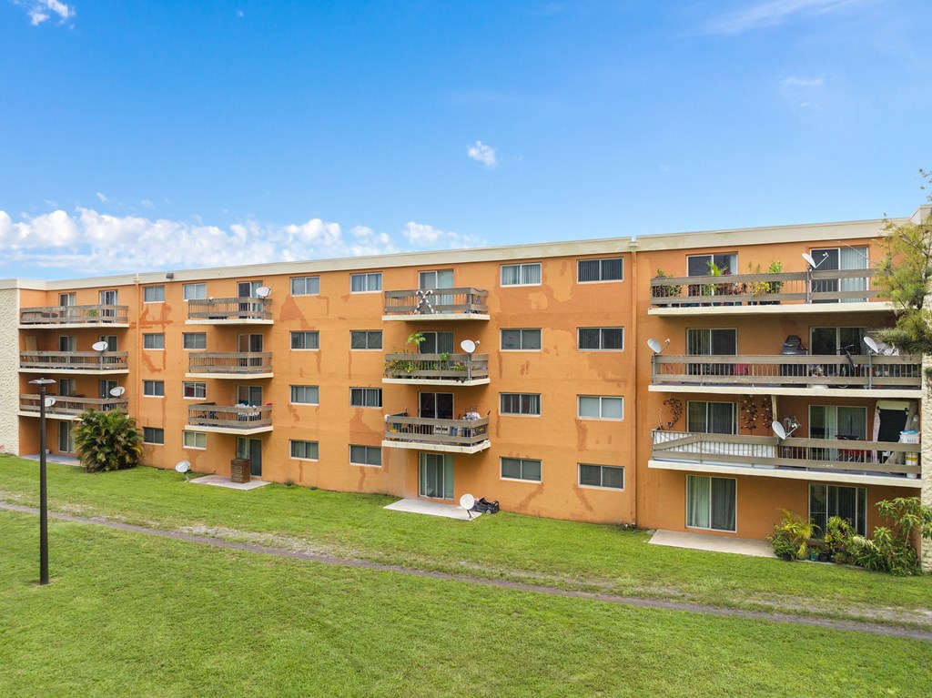 a large apartment building with balconies and a green lawn