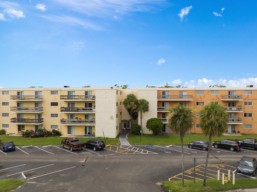 an apartment building with a parking lot and palm trees in front of it