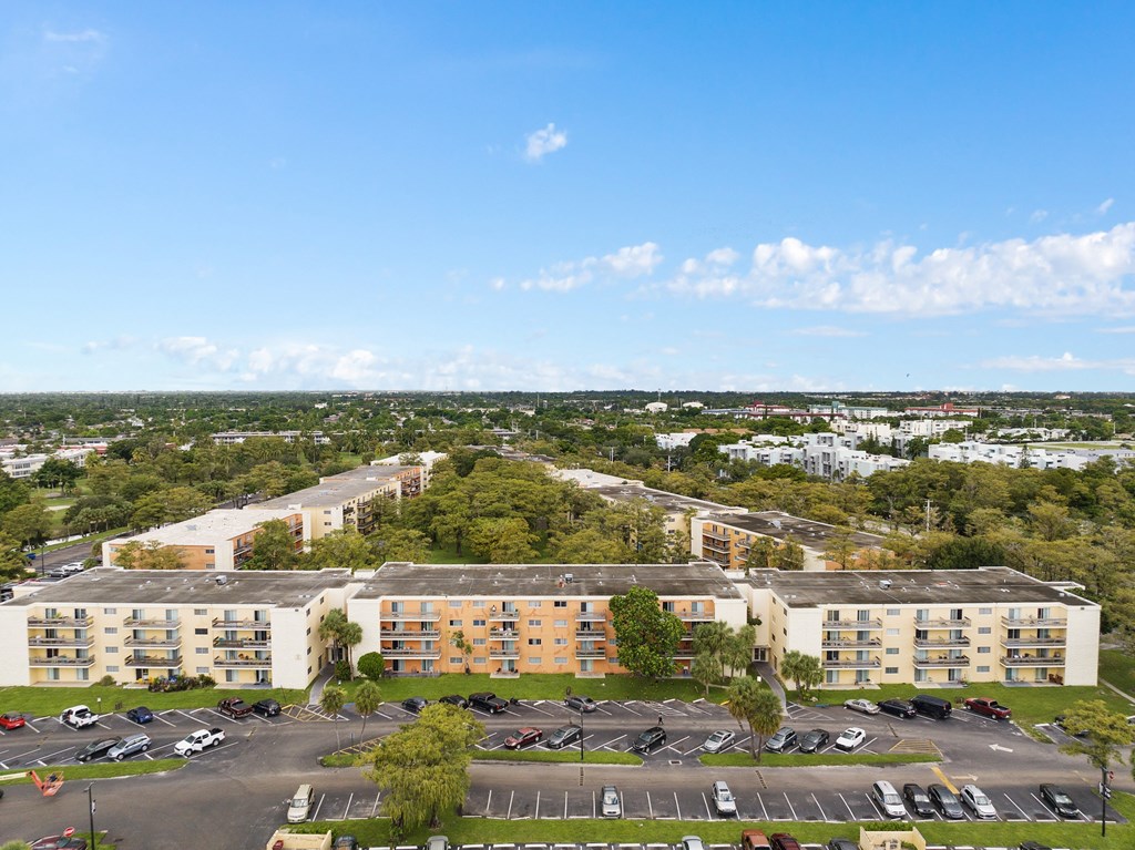 an aerial view of an apartment complex with a parking lot and trees