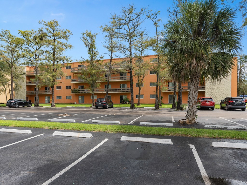 an apartment building with a parking lot and palm trees