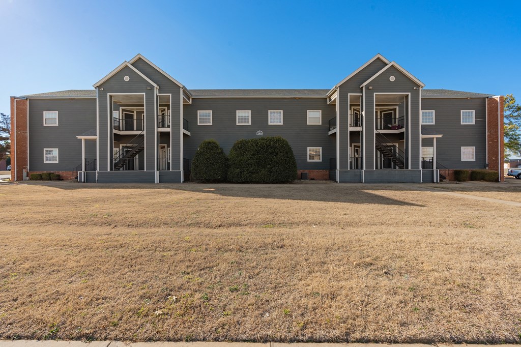 an exterior view of an apartment building with a large yard