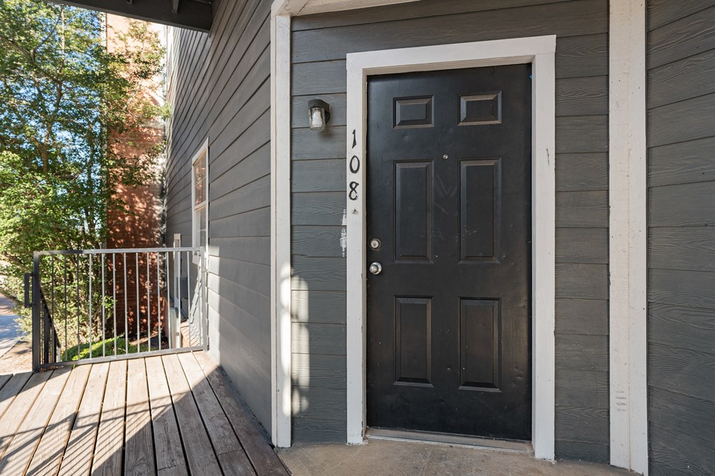 the front door of a gray house with a black door