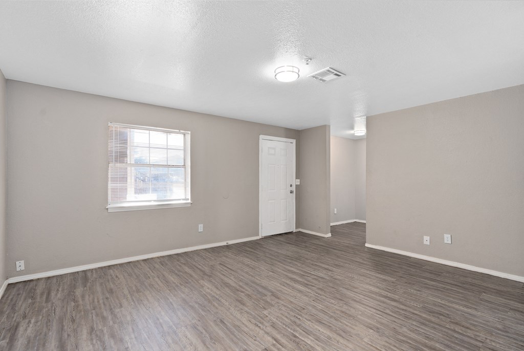 an empty living room with a white door and a window