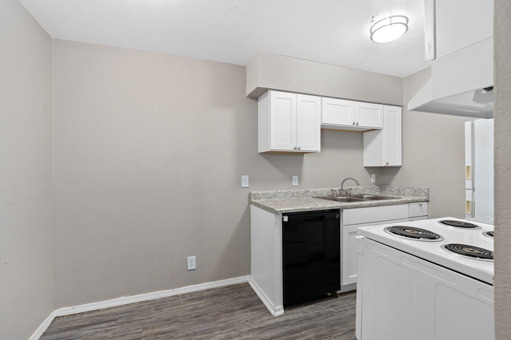 an empty kitchen with white cabinets and a black and white stove