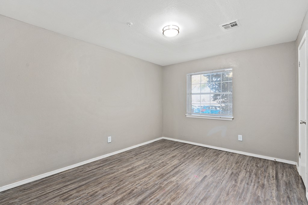 an empty room with wood flooring and a window