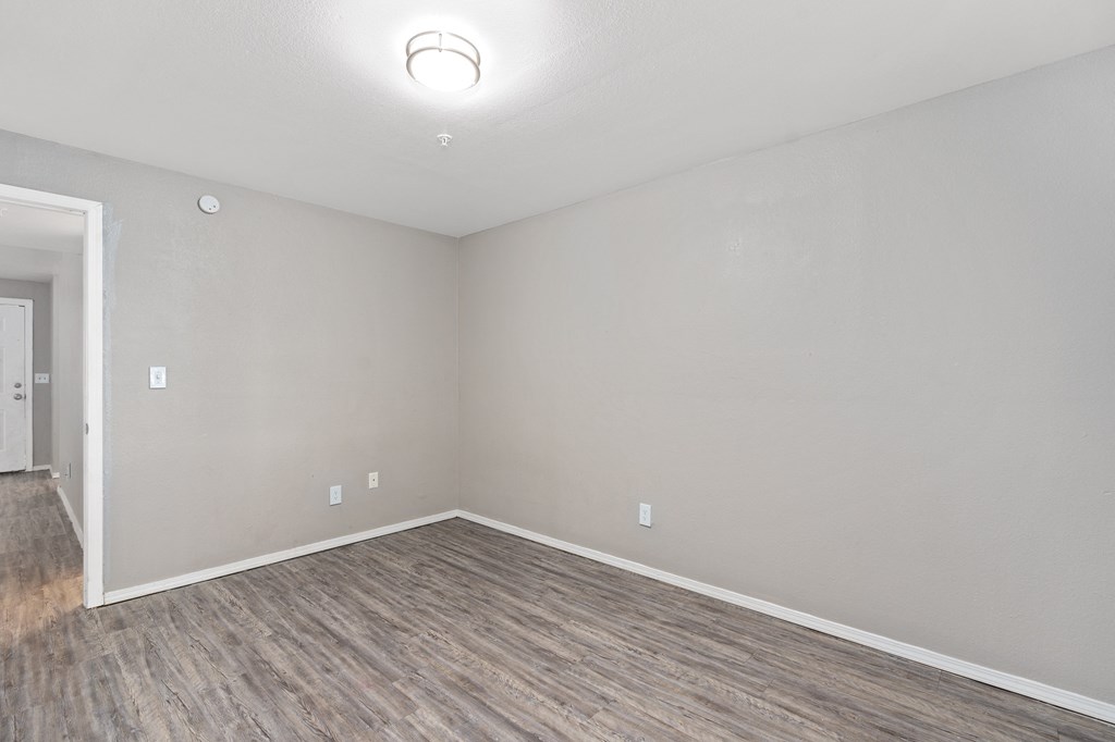 an empty living room with wood flooring and white walls