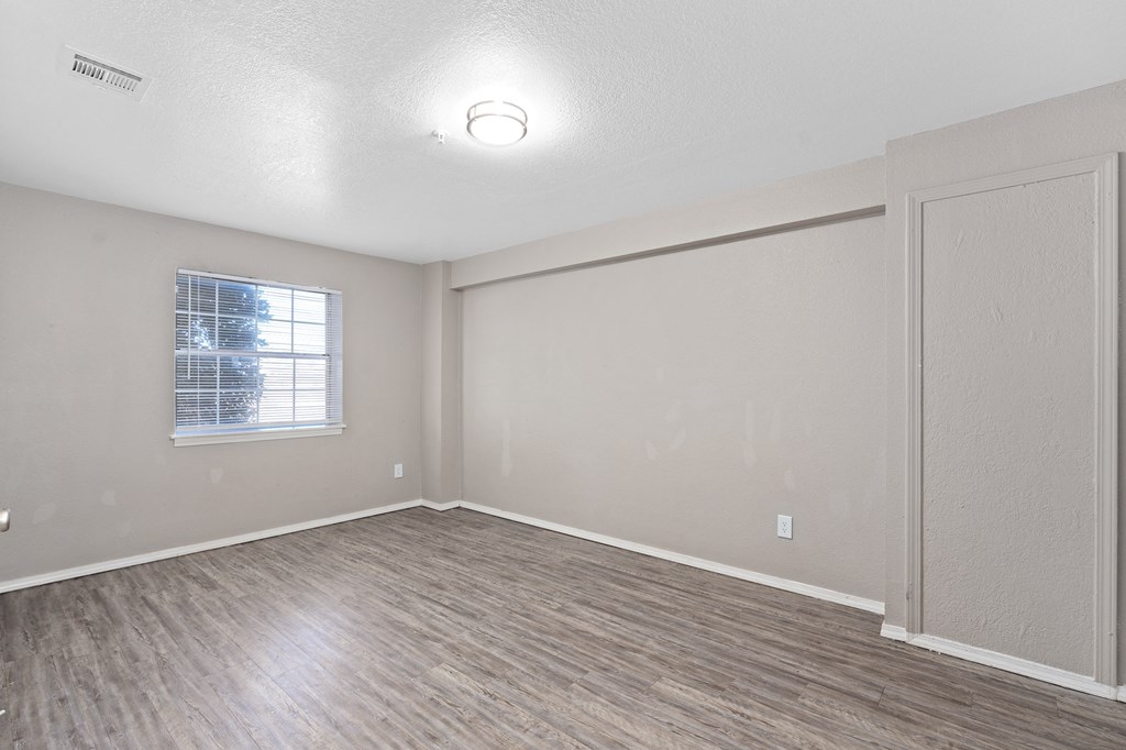 an empty living room with wood flooring and a window