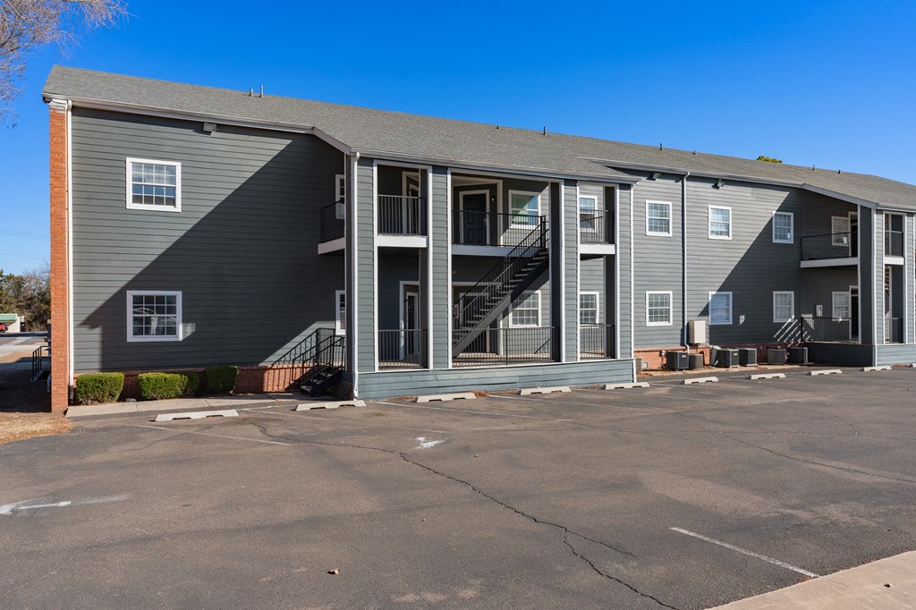 a gray apartment building with stairs and a parking lot