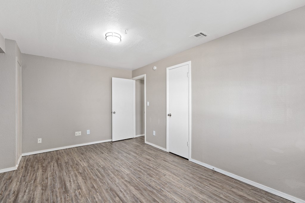 an empty living room with wood flooring and white walls