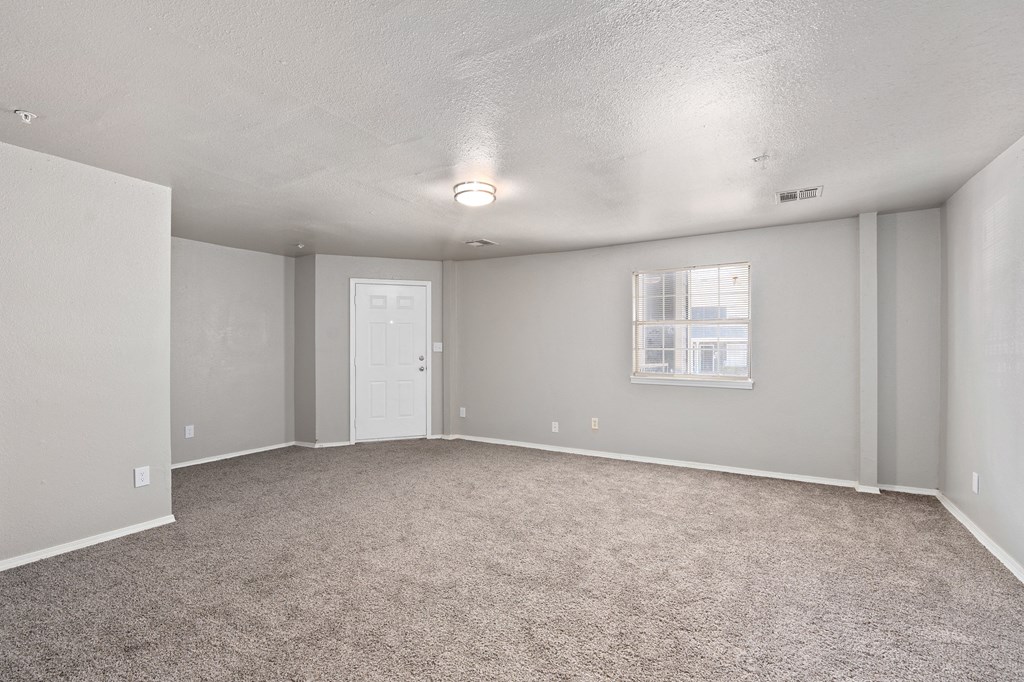 an empty living room with carpet and a white door