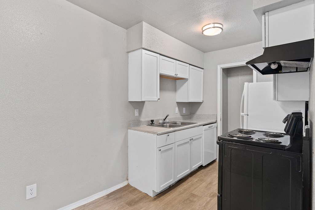 an empty kitchen with white cabinets and a stove and refrigerator