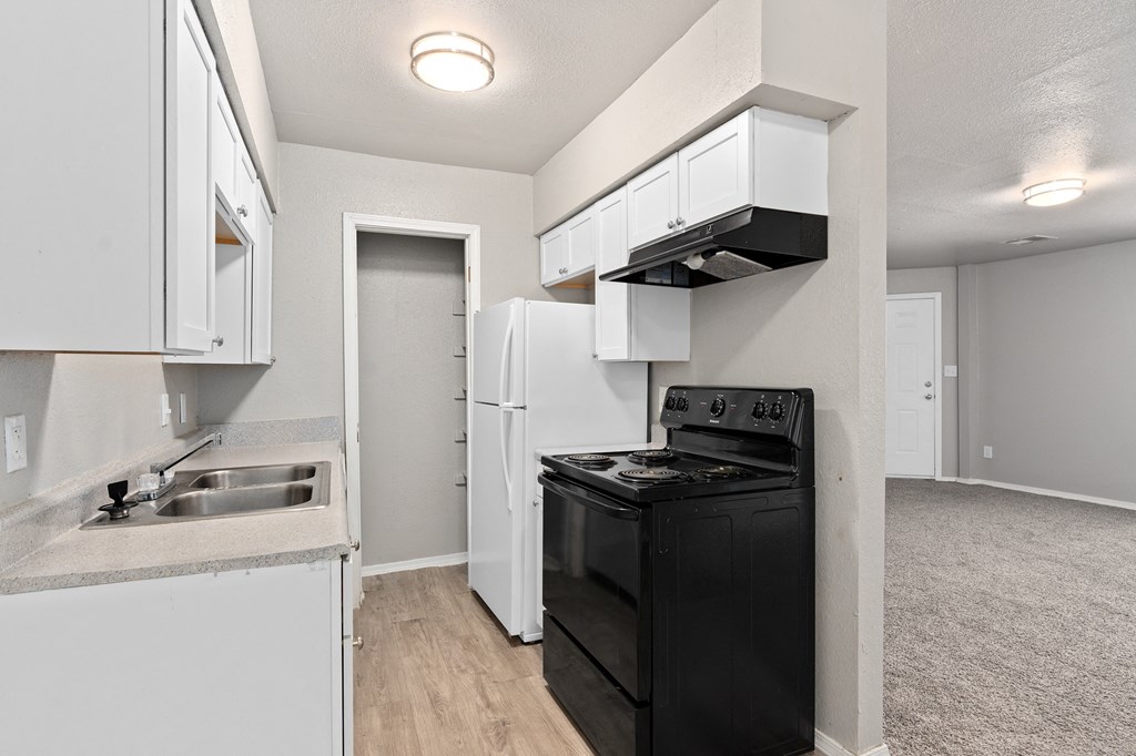 an empty kitchen with white cabinets and a black stove and refrigerator