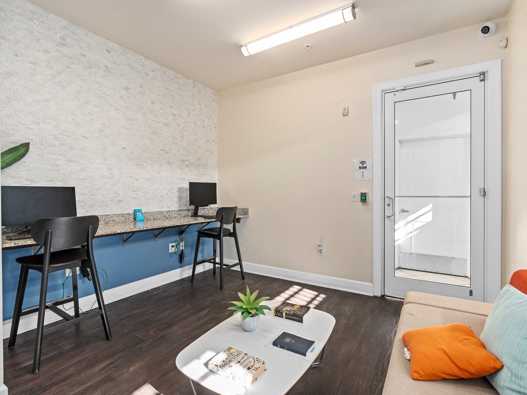 a living area with a couch and a desk with chairs and a door to a at Lake Lofts at Deerwood, Jacksonville, FL, 32216