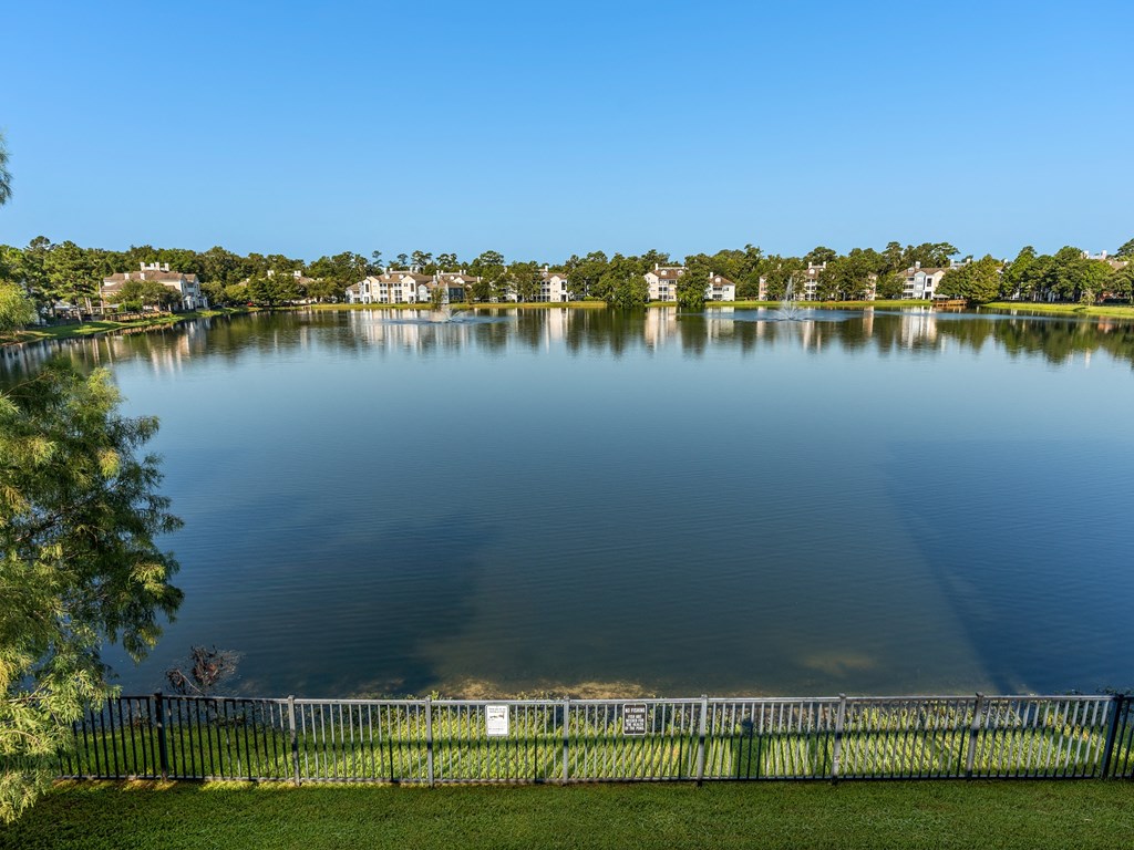a view of a lake with a fence and houses in the background at Lake Lofts at Deerwood, Jacksonville, FL, 32216