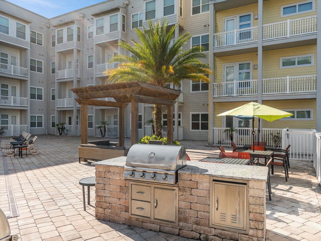 a large outdoor kitchen with a grill in front of an apartment building at Lake Lofts at Deerwood, Jacksonville, FL