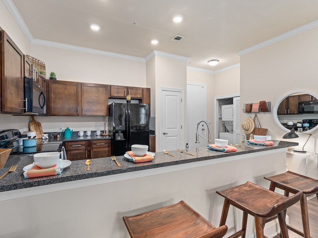 a kitchen with a bar and stools in front of a counter with a sink at Lake Lofts at Deerwood, Jacksonville