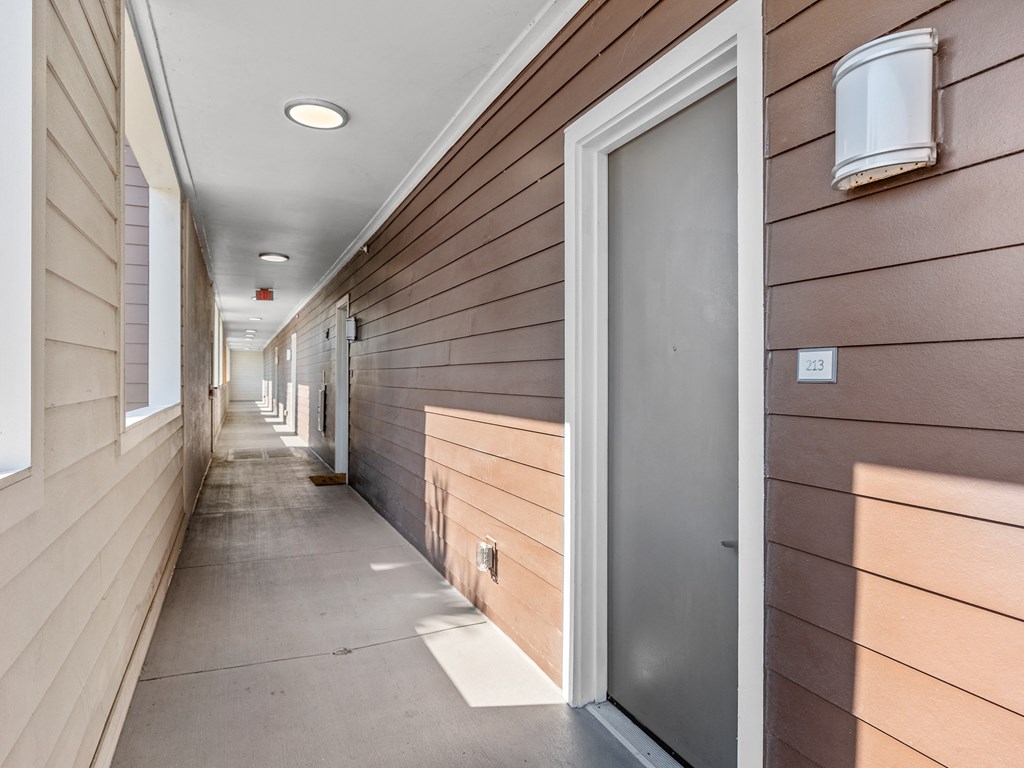 a long hallway with wood paneled walls and a silver door at Lake Lofts at Deerwood, Jacksonville