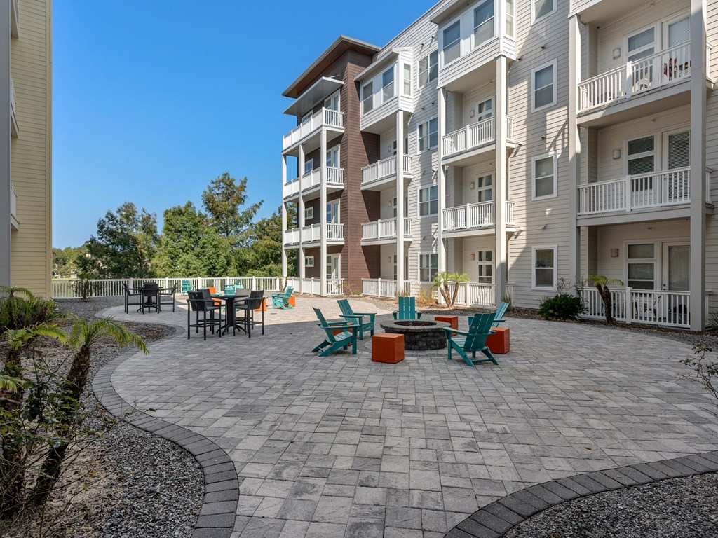 an outdoor patio with chairs and tables in front of an apartment building at Lake Lofts at Deerwood, Jacksonville, FL, 32216